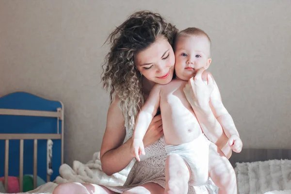 Moeder en babyboy zit op bed en knuffel — Stockfoto