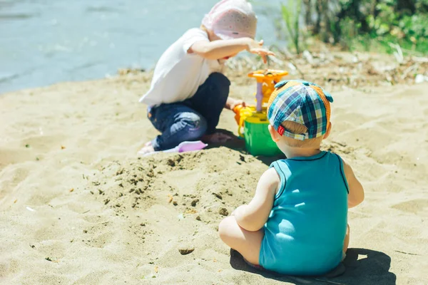 Dos bebés jugando en la playa con arena — Foto de Stock