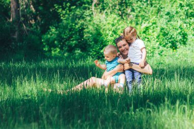 çimenlerin üzerinde iki çocuklu genç mutlu anne