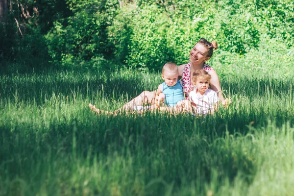 Giovane madre felice con due figli sull'erba — Foto Stock