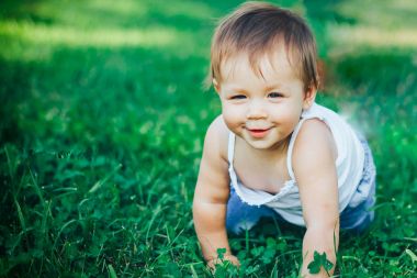 çimenlerin üzerinde mutlu sürünen bebek gitmek kamera ve smilind için