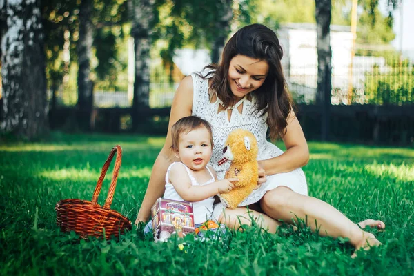 Lycklig mamma sitter med sin baby på gräs — Stockfoto