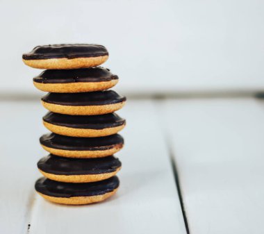 Beyaz ahşap zemin tanımlama bilgisi yığını. Yuvarlak bisküvi çikolata sır içinde. Birbirimizi üzerinde duruyor