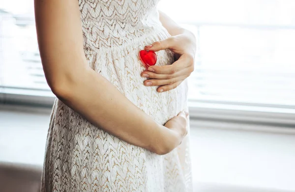 妊娠中の腹でハート型のプラスチック — ストック写真