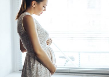 gebelik, dinlenme, insanlar ve beklenti kavramı - mutlu gülümseyen hamile kadının karnı evde dokunmadan yakın