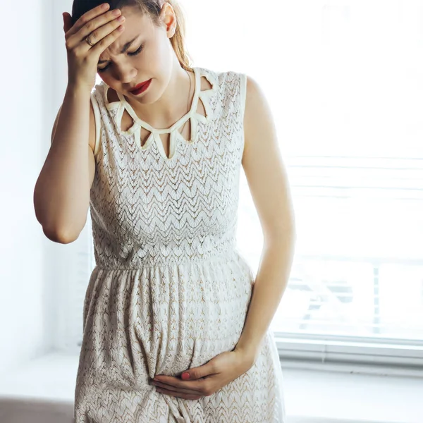 妊娠中の女性の肖像画は、自宅の窓の近くに頭痛 — ストック写真