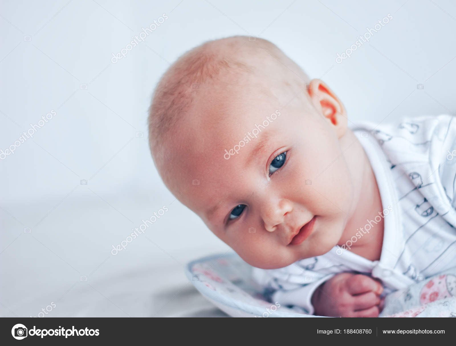 A Funny Baby With Beautiful Eyes Lies On His Stomach And Smiles