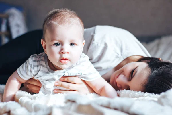 Bebekle yatağın üstüne oturan ve sarılma oynayan anne — Stok fotoğraf