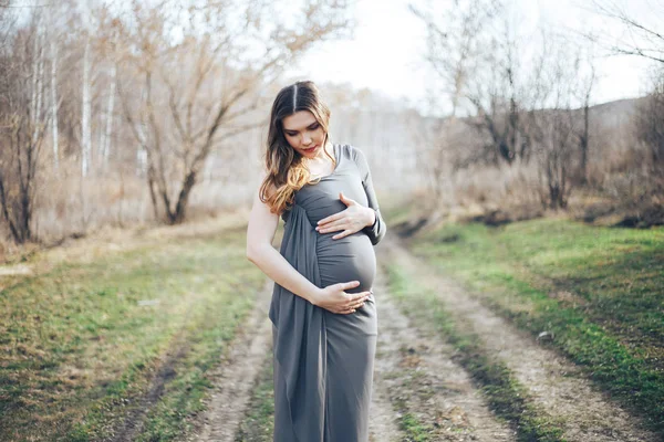 Donna incinta in abito grigio nella foresta — Foto Stock