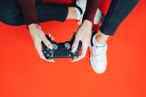 Young woman playing with gamepad on red.