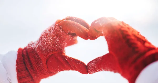 Жінка створює символ серця зі сніговими руками — стокове фото