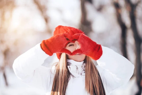 Frau bastelt Herz-Symbol mit schneebedeckten Händen — Stockfoto