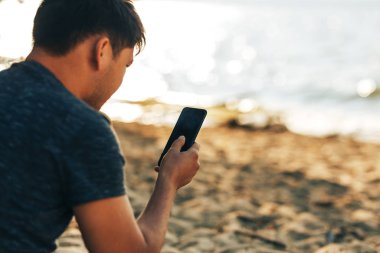 Young man looking at news and messaging and talking on his smart phone.