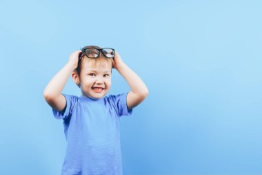 Kızgın küçük çocuk gözlüklü kameraya bakıyor.