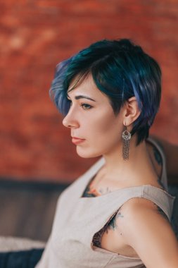 Güzel, yeşil, mor saçlı ve dövmeli bir kadın.