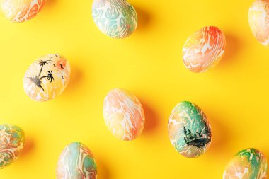 Turuncu ve yeşil renklerle boyanmış Paskalya yumurtaları sarı arka planda