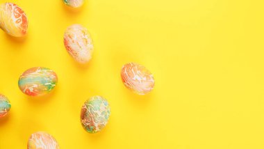 Turuncu ve yeşil renklerle boyanmış Paskalya yumurtaları sarı arka planda