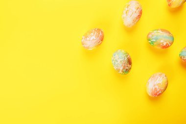 Turuncu ve yeşil renklerle boyanmış Paskalya yumurtaları sarı arka planda