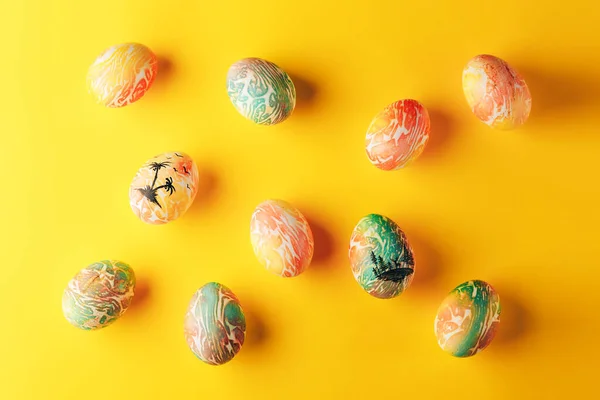 Easter eggs painted in orange and green colors on yellow background