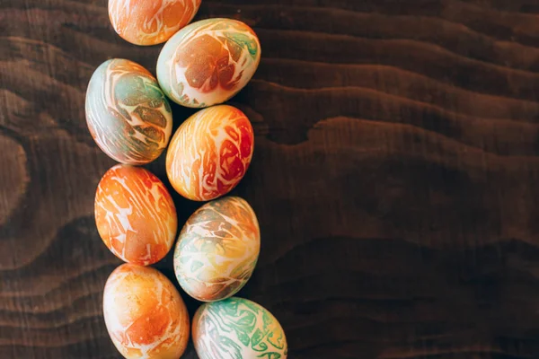 Renkli paskalya yumurtalarının üst görünümü farklı şekillerde. Ahşap arka planda yumurta çizgisi