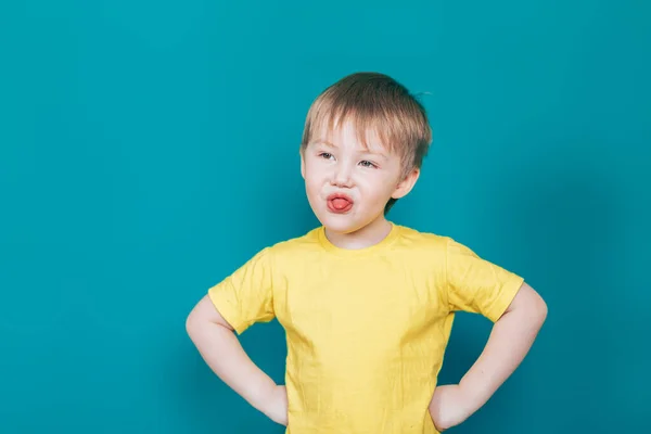 Küçük çocuk dilini sarı tişörtle gösteriyor. — Stok fotoğraf