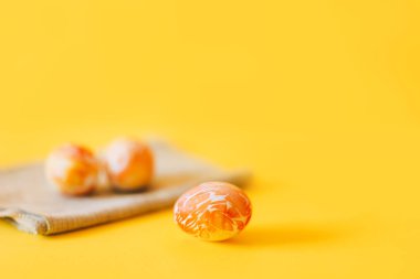 Üç portakal boyalı paskalya yumurtası, yeşil peçeteyle..