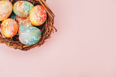 Pastel pembe arka planda yuvadaki Coloeful Paskalya yumurtaları.