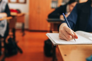 Öğrenci bir not defterinde yazıyor