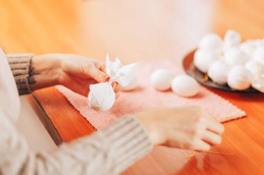 Paskalya 'ya hazırlanan kadın, peçetelerin yardımıyla yumurta boyuyor..