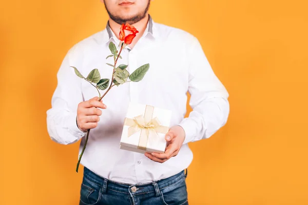 Мужчина держит в руках цветок и подарок — стоковое фото