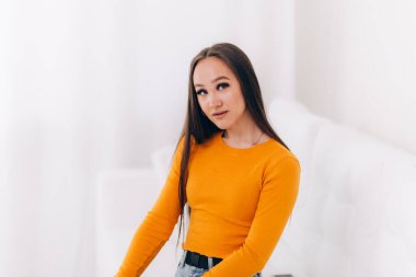 Beyaz odadaki beyaz kanepede oturan güzel kız.