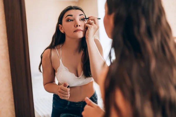 Joven hermosa chica hace un maquillaje — Foto de Stock