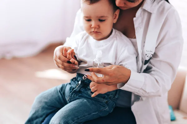 Moeder met een kind wrijft hun handen met een sanitizer — Stockfoto