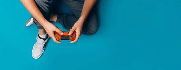 Jovem Joga Videogames Suas Mãos Segurando Gamepad Vermelho Fundo Azul — Fotografia de Stock