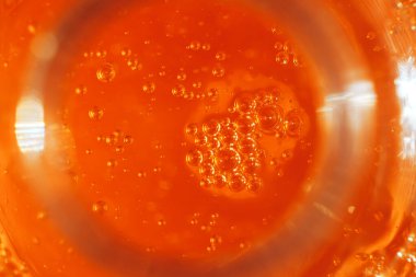 Turuncu arka planda bir sürü küçük baloncuk, makro sıvı sabun, makro bardakta bira, meyve suyu ve makro kokteyl..