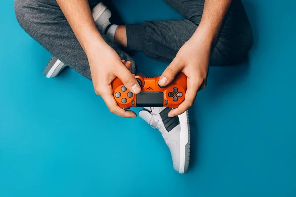 Jovem Joga Videogames Suas Mãos Segurando Gamepad Vermelho Fundo Azul — Fotografia de Stock