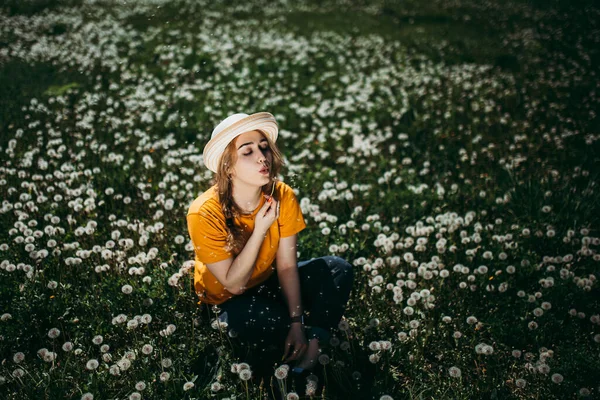# Turuncu tişörtlü genç bir kız # # Karahindibaların yetiştiği çimlerde uzanıyor # — Stok fotoğraf