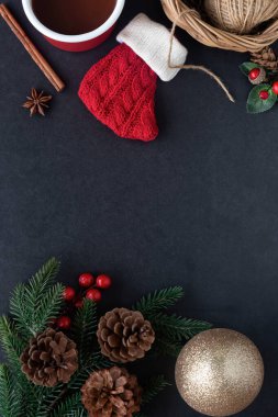Siyah granit süsleme kırmızı çorap, çam yaprağı ve koni, kutsal toplar, altın top ve bir fincan çikolatayla Noel konseptinde. En üstteki görünümde arkaplan noel duvar kağıdı için kopya alanı ile yatıyordu.