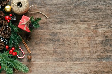 Ahşap desen Noel konseptinde çam yaprakları, kozalaklar, kutsal toplar, hediye kutusu ve şeker kamışlarıyla süslenir. Üst görünümde eski ahşap arkaplan. Noel duvar kağıdı için fotokopi alanı var..