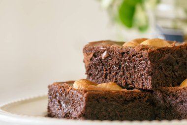 Beyaz tabakta fındıklı, üzerinde fotokopi alanı olan siyah çikolatalı brownie. Lezzetli, acı tatlı, çiğnenmiş ve şekerli. Brownie çikolatalı kekin bir çeşidi. Ev yapımı fırın konsepti