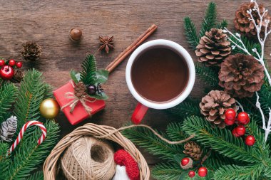 Tahta döşeme, çam yaprağı, kozalak, kutsal toplar, şeker kamışı ve kırmızı bardak çikolatayla süslenmiş. Üst görünümde ahşap arkaplan noel duvar kağıdı için kopyalama alanı ile yatıyordu.