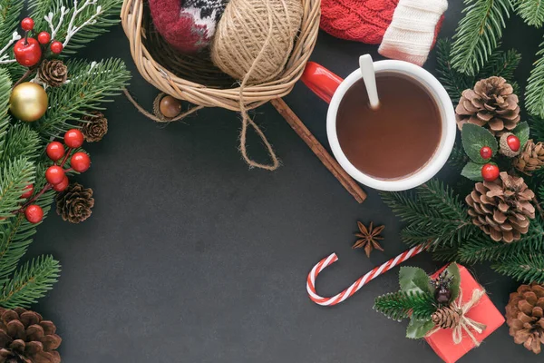 Siyah granit masa hediye kutusuyla süslenmiş, çam yaprağı ve kozalaklar, kutsal toplar ve Noel konseptinde bir fincan çikolata. En üstteki görünümde arkaplan noel duvar kağıdı için kopya alanı ile yatıyordu.
