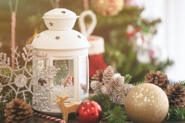 Beyaz fener, çam yaprağı, çam kozalağı, kar tanesi, şeker kamışı, balo ve ahşap masadaki değerli ren geyiği ile süslenmiş Noel süsü. Xmas kutlaması için Bokeh Noel ağacı duvar kağıdı.