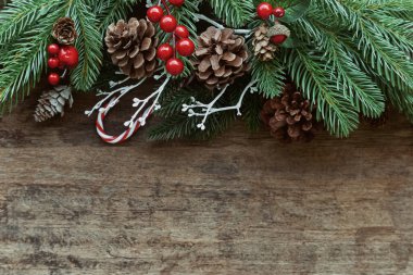 Eski ahşap desen, Noel temalı çam yaprakları, kozalaklar, kutsal toplar ve şeker kamışlarıyla dekore edilir. Üst görünümde eski ahşap arkaplan. Noel duvar kağıdı için fotokopi alanı var..