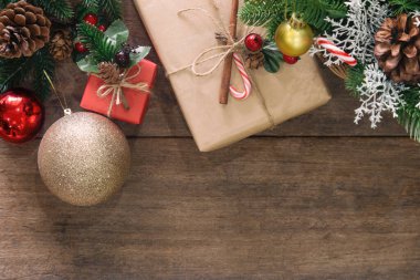 Ahşap tahta döşeme, çam yaprakları ve kozalaklarla süslenmiş, kutsal toplar, parıltılı altın top ve Noel konseptinde hediye kutusu. En üstteki görünümde arkaplan noel duvar kağıdı için kopya alanı ile yatıyordu.