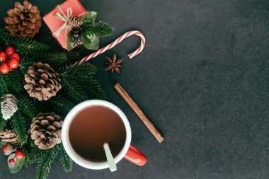 Siyah granit masa hediye kutusuyla süslenmiş, çam yaprağı ve kozalaklar, kutsal toplar ve Noel konseptinde bir fincan çikolata. En üstteki görünümde arkaplan noel duvar kağıdı için kopya alanı ile yatıyordu.