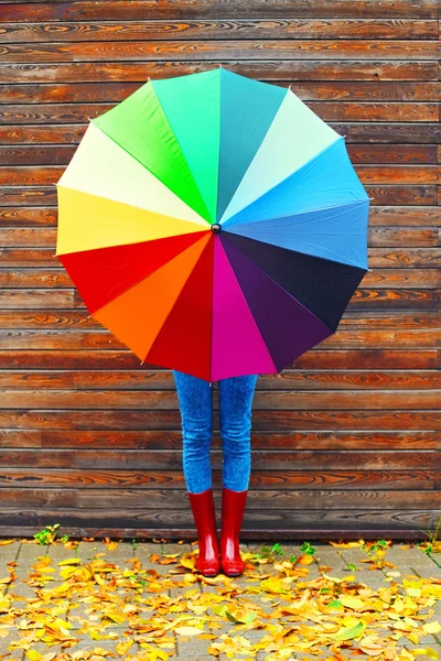 Φθινοπωρινή φωτογραφία γυναίκα κρατώντας πολύχρωμο ομπρέλα φορώντας ένα κόκκινο rubbe — Φωτογραφία Αρχείου