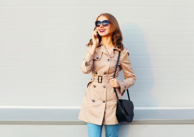 Çok gülümseyen genç kadın bir palto giyiyor Smartphone'da söz 