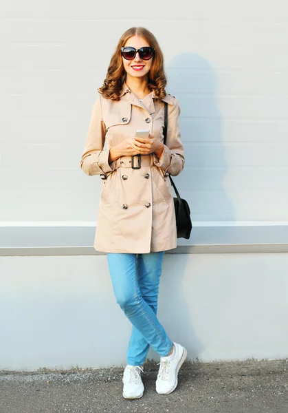 Moda encantadora joven sonriente mujer usando teléfono inteligente con un co —  Fotos de Stock