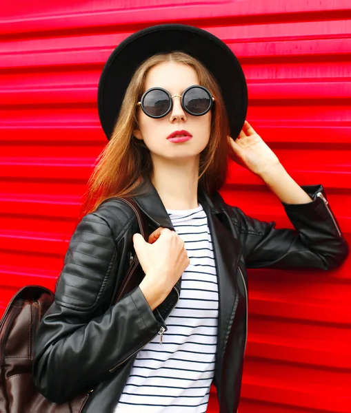 Fashion portrait young woman in black rock style stands over red — Stock Photo, Image